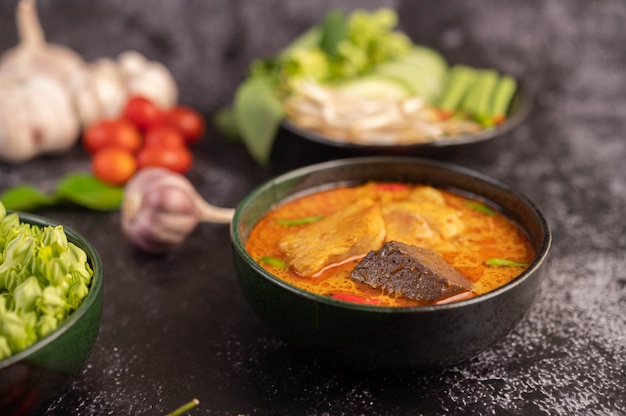 Chicken curry in a black cup with rice noodles.