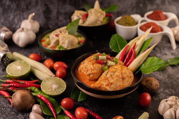 Chicken curry in a bowl with lemongrass, kaffir lime leaves, tomatoes, lemon, and garlic