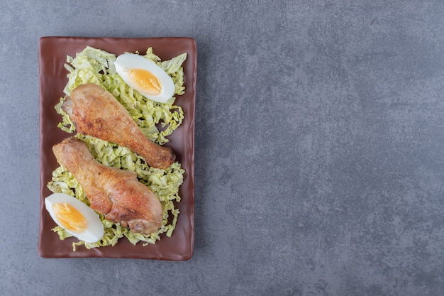 Free Photo chicken drumsticks and boiled eggs on brown plate.