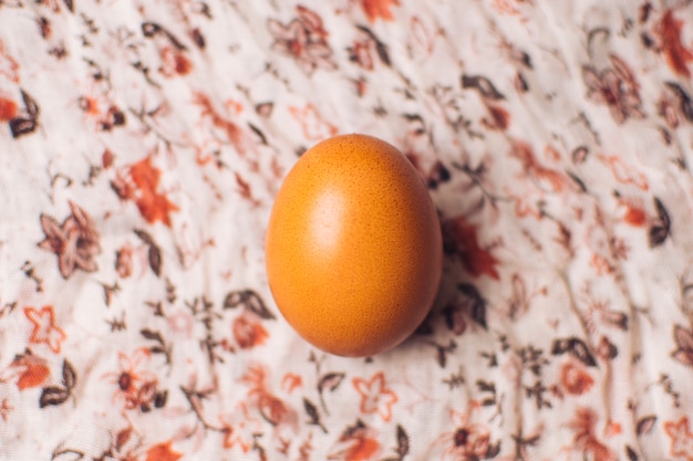 Free photo chicken egg on flowered textile