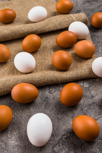 Chicken eggs scattered on canvas on grey table