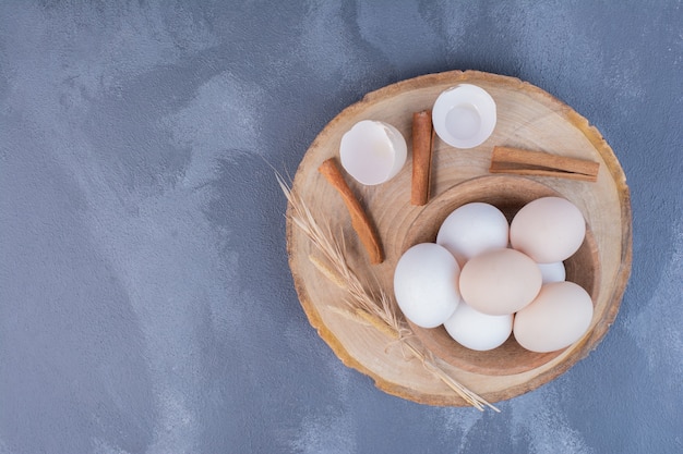 Chicken eggs with eggshells on wooden platter