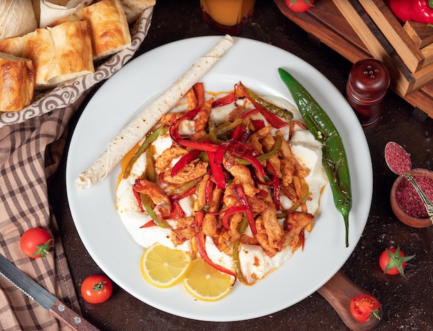 Chicken fajita, chicken fillet fried with bell pepper in lavash with bread slices in white plate 