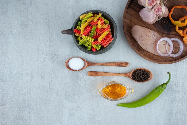 Chicken fillet and vegetables on wooden plate with macaroni.