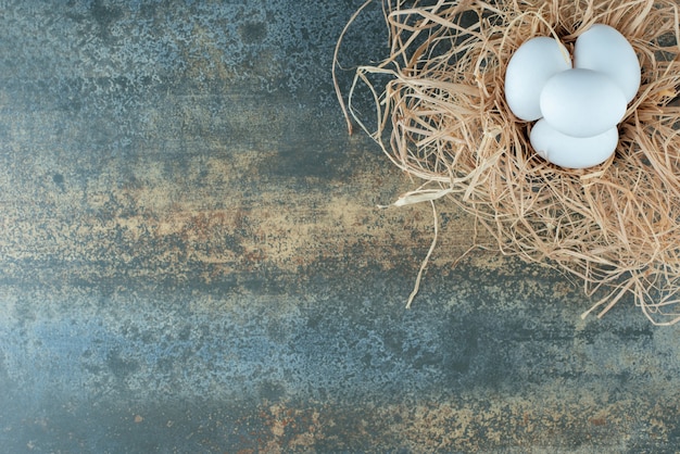 Free photo chicken fresh white eggs lying in hay on marble background