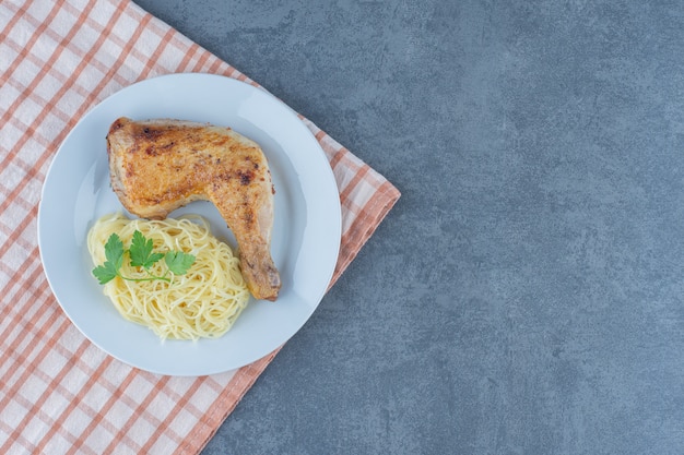 Chicken leg and spaghetti on white plate. 