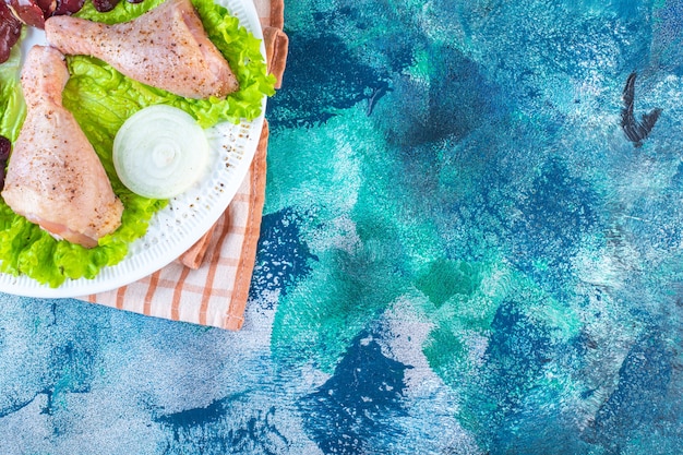 Free Photo chicken liver, lettuce leaves and chicken drumstick on a plate on the tea towel