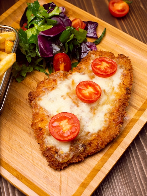 Chicken nuggets, french fries. Fried nuggets and potato with salad and melted cheese. 