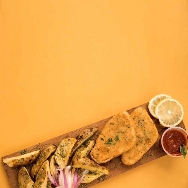 Free photo chicken nuggets and potato wedges arranged on wooden board