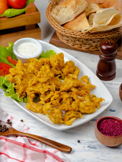 Chicken nuggets served with mayonnaise yogurt sauce inside white plate with lettuce and tomatoes