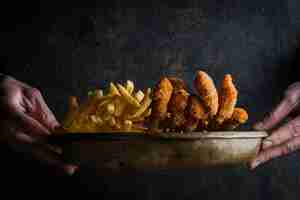 Free photo chicken nuggets with french fries and human hand in clay dishes