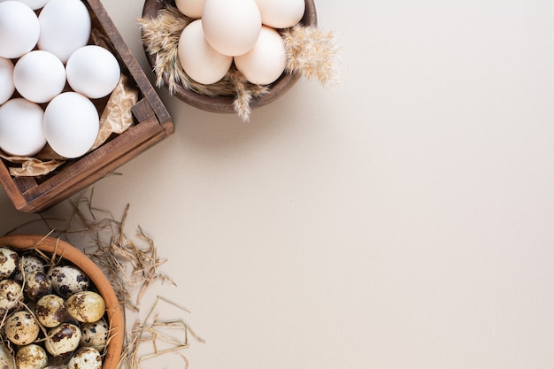 Chicken and quail raw eggs placed on beige table.