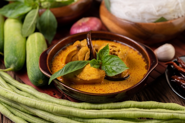 Free Photo chicken red curry in a bowl with dried chilies, basil, cucumber and long beans