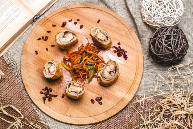 Chicken roll on wooden board mix bell pepper with greens top view