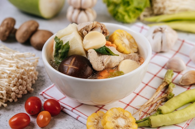 Chicken soup with corn, shiitake mushroom, enoki mushroom, and carrot.