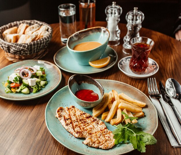 Chicken steak with french fries and ketchup served with soup and vegetable salad