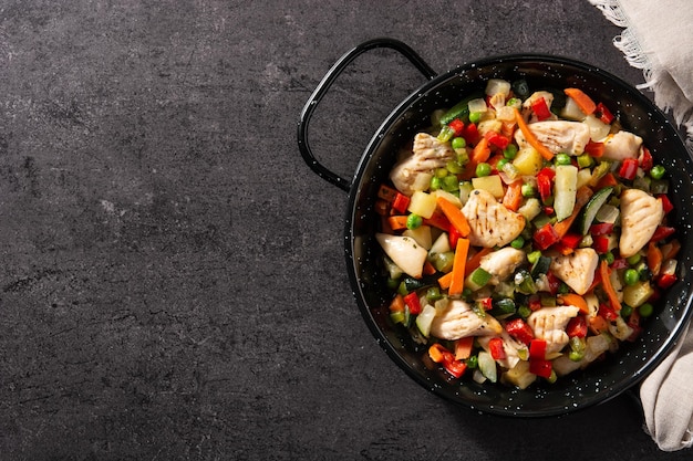 Free photo chicken stir fry and vegetables on black stone background