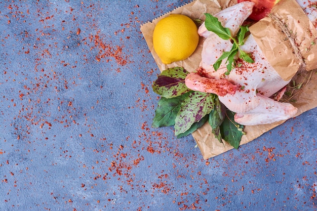 Chicken with spices on a wooden board on blue