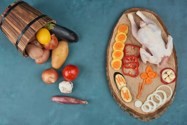 A chicken with vegetables on a wooden board.