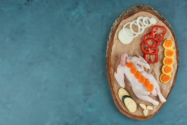 Free Photo chicken on a wooden platter with vegetables.