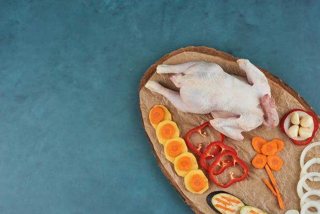 Chicken on a wooden platter with vegetables.