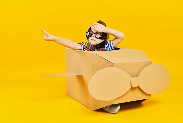 Free photo child as astronaut in toy plane pointing