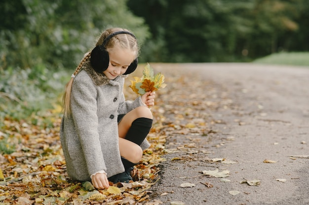 Child in a autumn park. Kid in a gray coat.