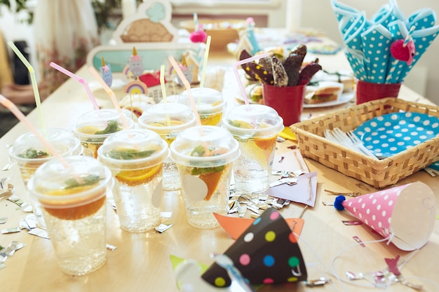 Child birthday decorations. Pink table setting from above with cakes, drinks and party gadgets.