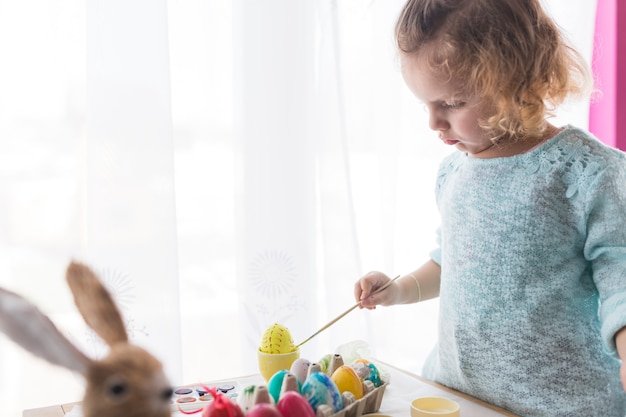 Free photo child decorating easter egg