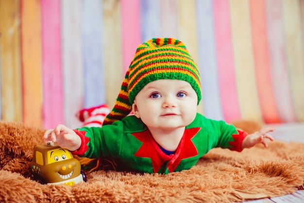 Child dressed like an elf lies on fluffy carpet