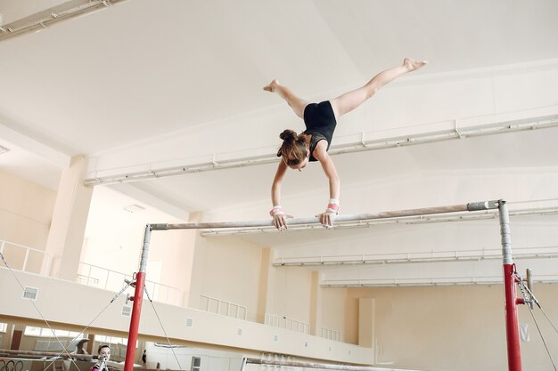 Child gymnastics balance beam.  Girl gymnast athlete during an exercise horizontal bar in gymnastics competitions.