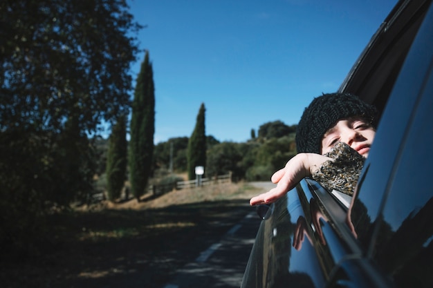 Free photo child hanging out of car window