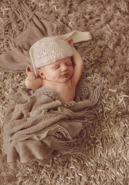 Free photo child in hat like rabbit ears sleeps on fluffy carpet