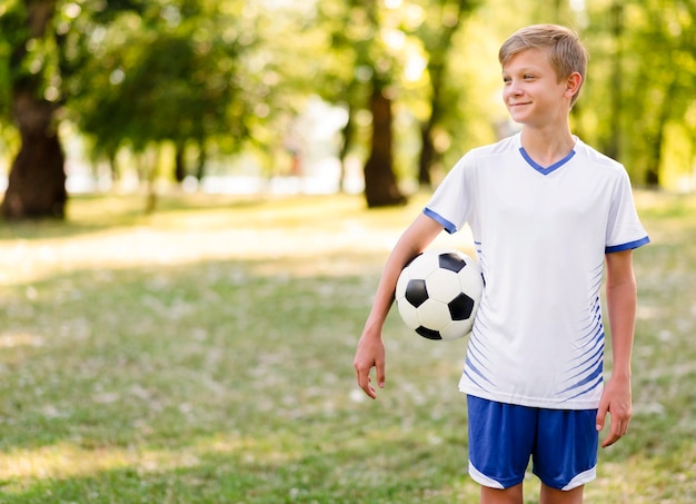 Child holding a football outdoors with copy space