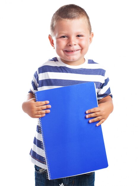 Child smiling with a blue notebook