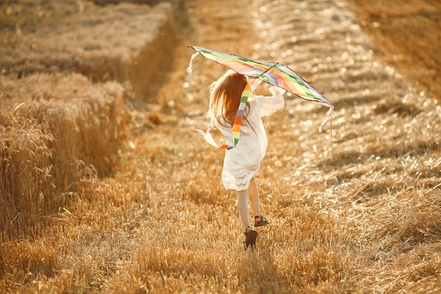 Free Photo child in a summer field. little girl in a cute white dress. child with a kite.