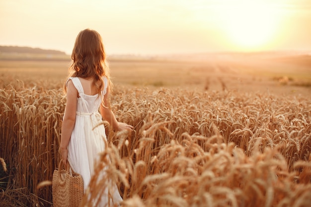 Child in a summer wheat field. Little girl in a cute white dress.