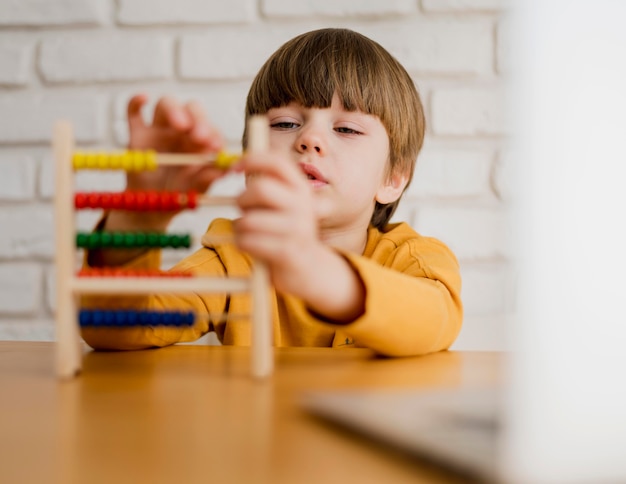 Child using abacus at home with laptop