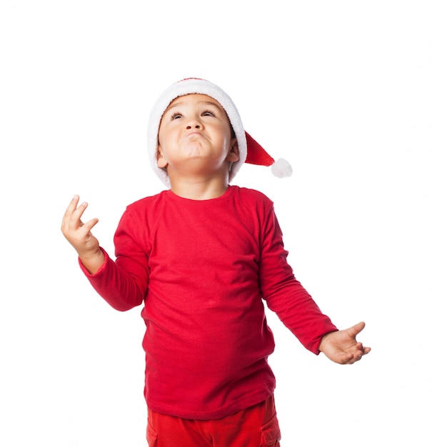 Free photo child wearing christmas hat with confusion gestures