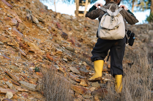 Free photo child with backpack climbing on hill