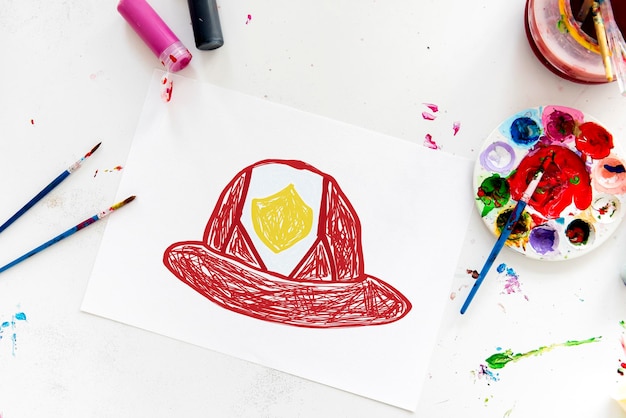 Free photo child with a drawing of firefighter helmet