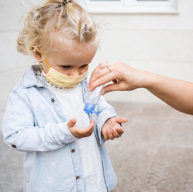 Free Photo child with medical mask getting hand sanitizer