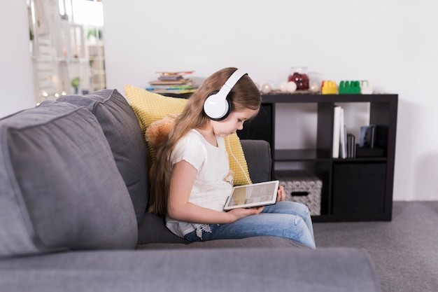 Child with tablet on sofa