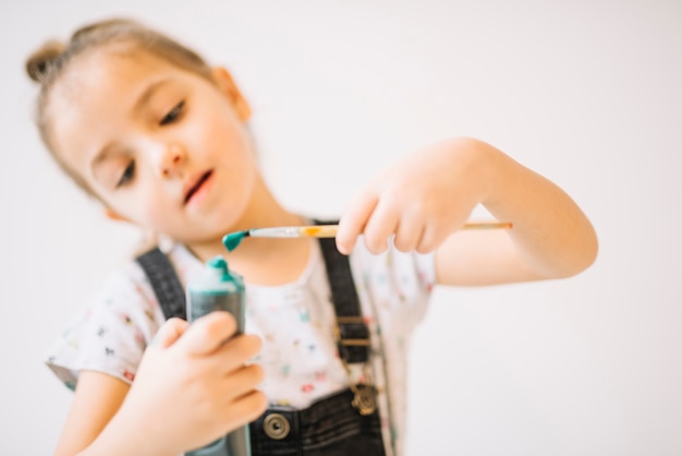 Free photo child with tube of colors and brush in hands