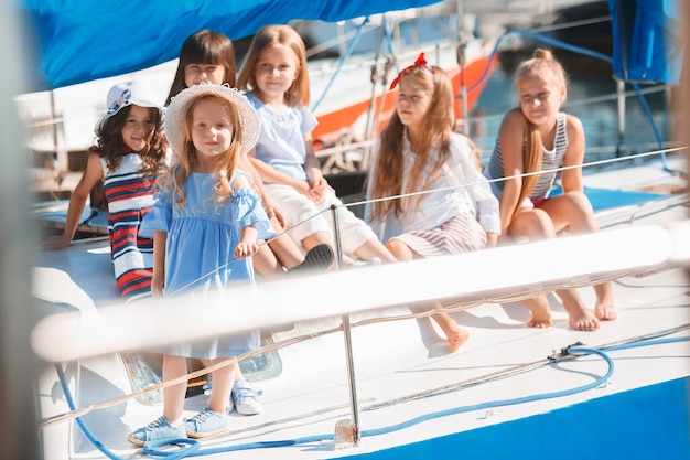 Free Photo the children on board of sea yacht drinking orange juice. the teen or child girls against blue sky outdoor. colorful clothes. kids fashion, sunny summer, river and holidays concepts.