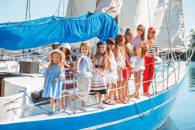 Free Photo the children on board of sea yacht drinking orange juice. the teen or child girls against blue sky outdoor. colorful clothes. kids fashion, sunny summer, river and holidays concepts.