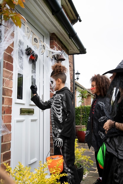 Free photo children in costumes trick or treating at someone's house