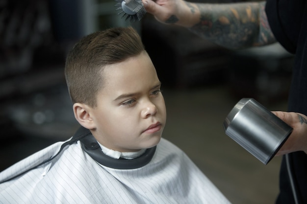 Children hairdresser cutting little boy