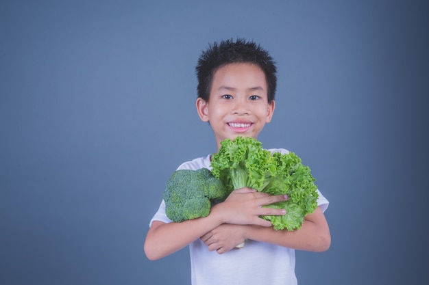 Children holding vegetables on a gray background.