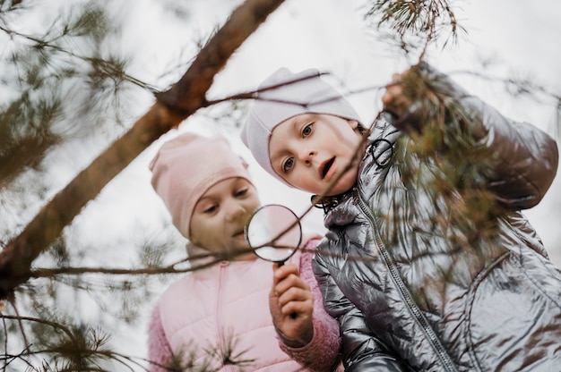 Children learning science in the nature with a magnifier